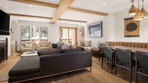 A modern living room with a dark grey sectional sofa, a wooden dining table with chairs, and a fireplace. - Vail Village Luxury 4 Bedroom, Steps to Slopes! (Vail)