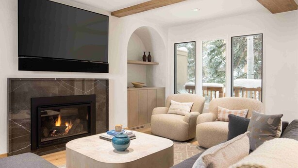 A modern living room with a fireplace, comfortable seating, and large windows offering a view of the outdoors. - Vail Village Luxury 4 Bedroom, Steps to Slopes! (Vail)