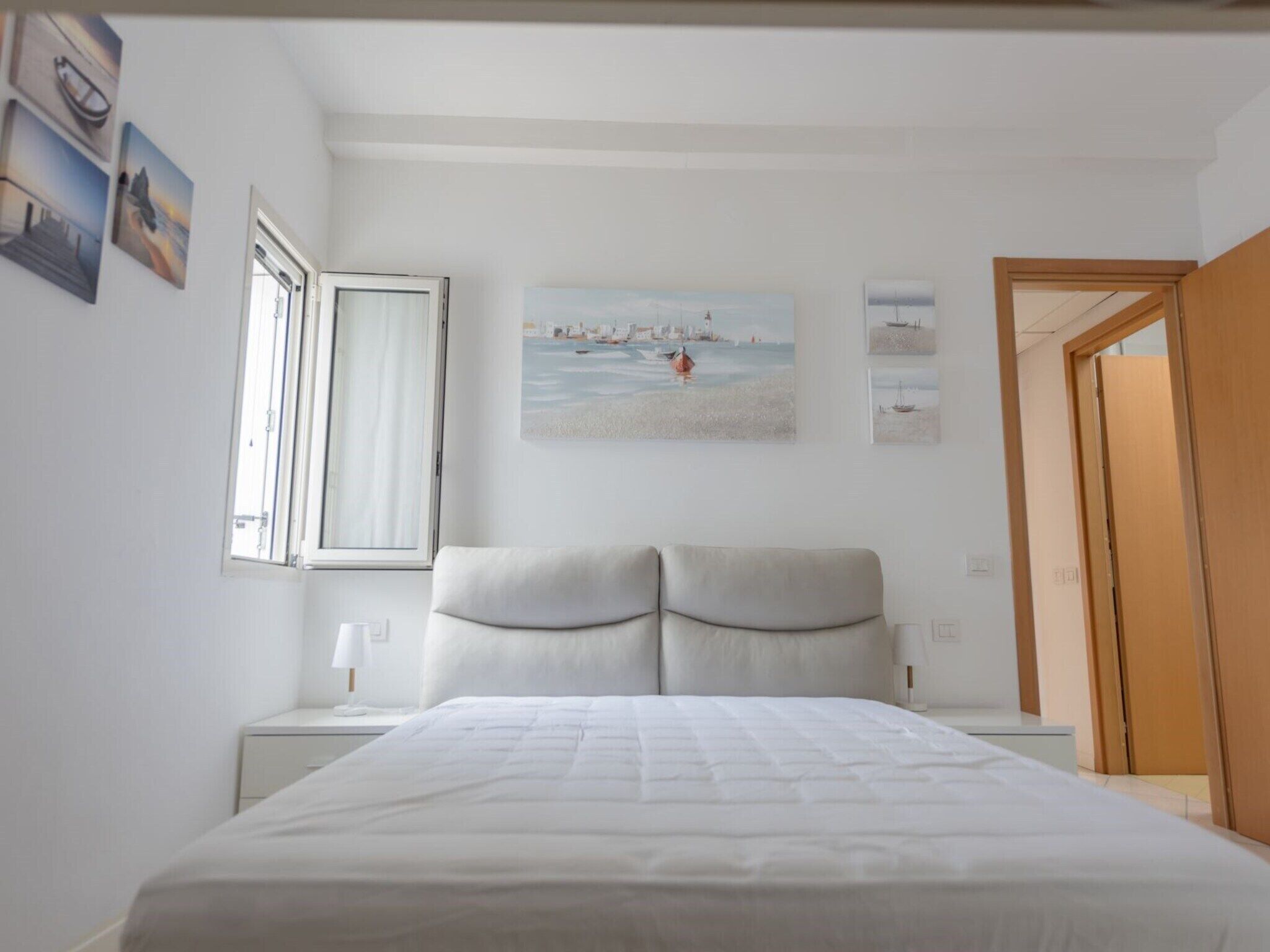 Une chambre à coucher avec un lit, une table de chevet, une fenêtre et une porte.