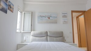 Ein Schlafzimmer mit Bett, Nachttisch, Fenster und Tür.