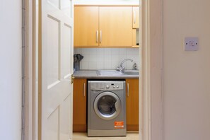 Una cucina compatta con mobili in legno, una lavatrice e un lavandino.