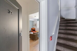 A modern interior with a staircase, a door with a number, and a living area with a sofa and a chair.