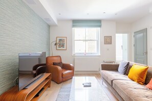 A living room with a flat-screen TV, leather armchair, sofa, and a coffee table.