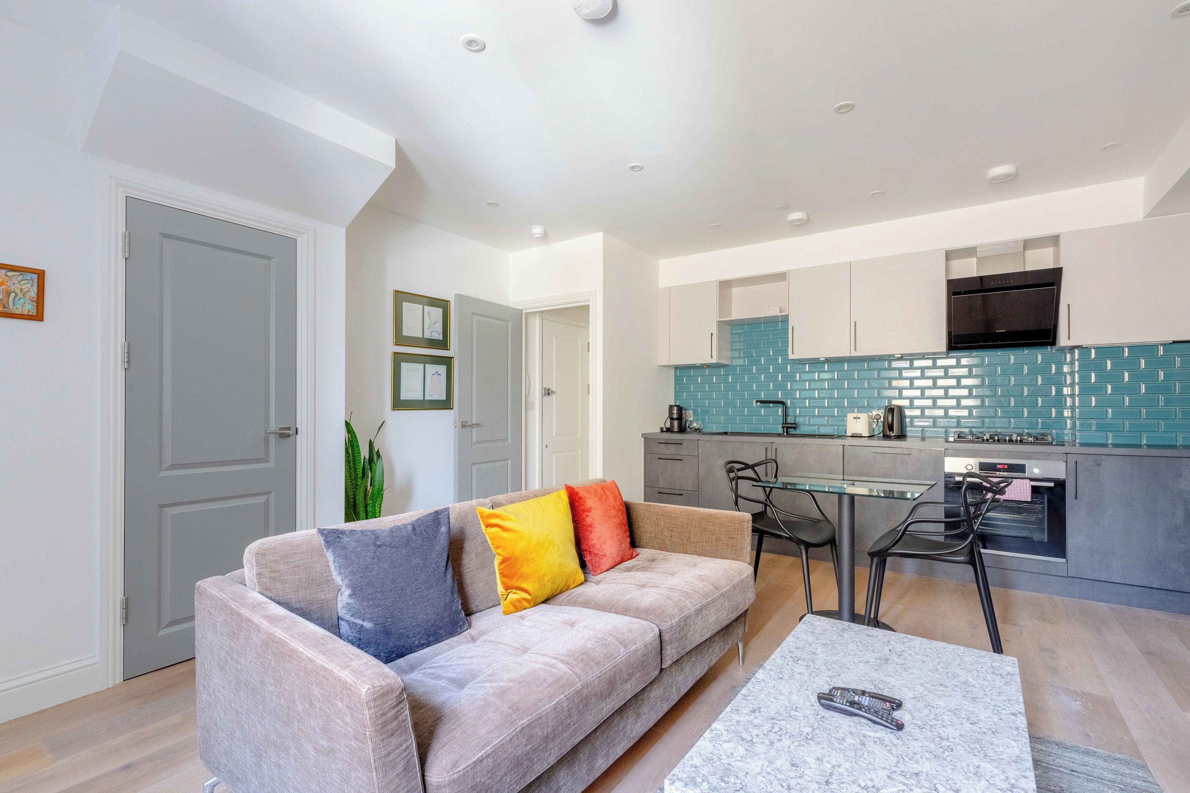 A modern apartment with a living room, kitchenette, and a dining area.