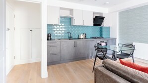 Eine moderne Küche mit grauen Schränken, einer blauen Fliesenrückwand und einer schwarzen Dunstabzugshaube.