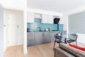 Una cucina moderna con mobili grigi, zoccolo di piastrelle blu e cappa aspirante nera.