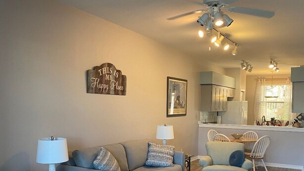 A living room with a sofa, ottoman, coffee table, and a ceiling fan.