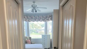 A bedroom with a bed, dresser, and window with a view.