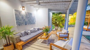 Un espace de détente extérieur moderne, comprenant un canapé, des fauteuils et des plantes en pot.