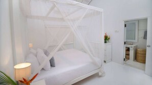Une chambre avec un lit à baldaquin, une table de chevet, un miroir et une vue sur la salle de bain.