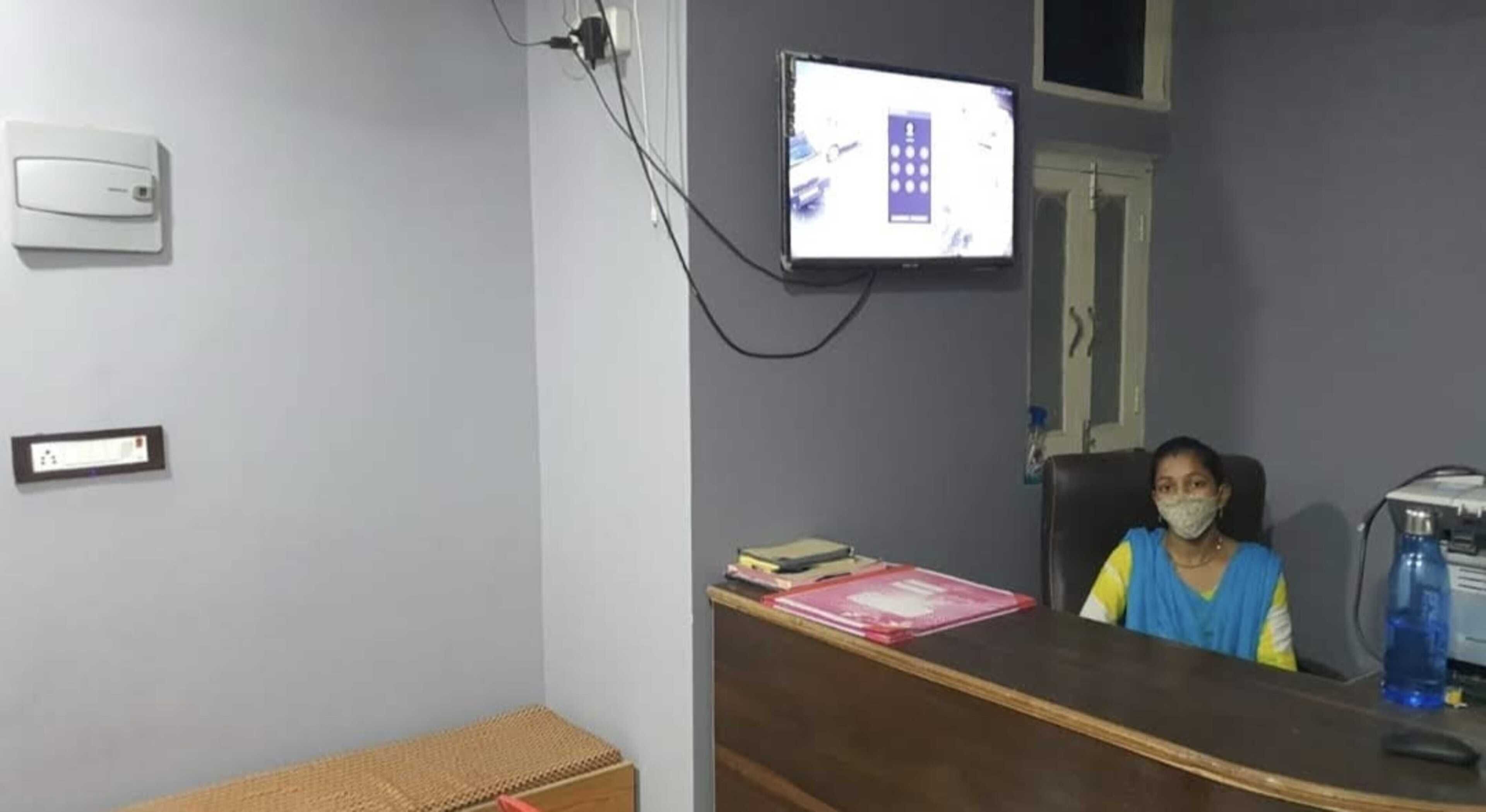 A room with a desk, a computer monitor, and a chair. There are books and a water bottle on the desk.