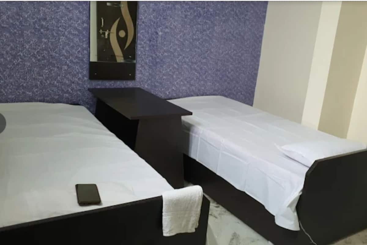 A room with two beds, a small table, and a wall-mounted artwork.
