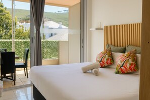 A hotel room with a bed, a chair, and a view of the outdoors. - Sweet Stay (Cape Town)