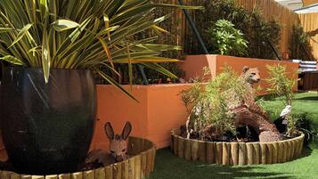 A garden with a large potted plant, a wooden fence, and a small animal figurine.