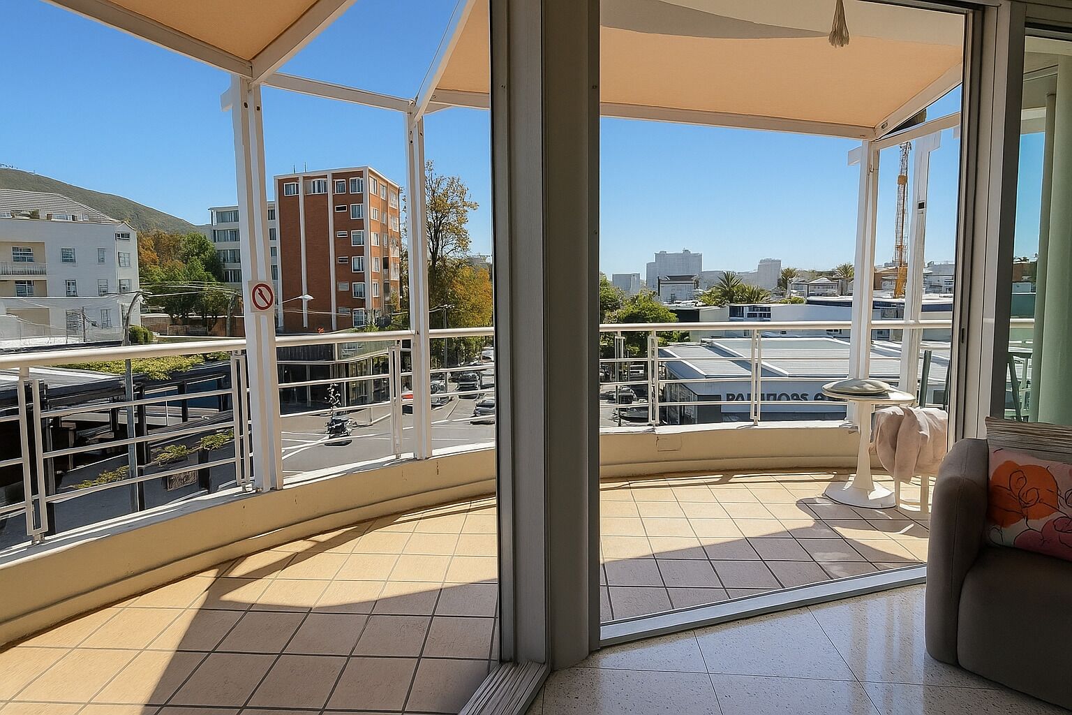 A balcony with a view of a cityscape, including buildings and a no-parking sign.