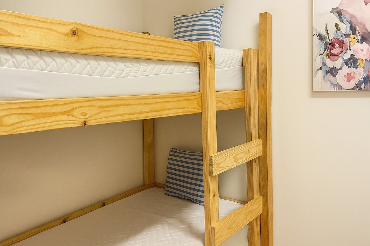 Un lit superposé avec une structure en bois, un matelas et un oreiller.