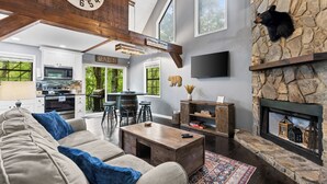 A spacious living room with a fireplace, a large clock, and a stone wall with a bear decoration. - Winter Retreat, Hot Tub, Fire Pit, 7min to Ellijay. 16min to Blue Ridge (Ellijay)