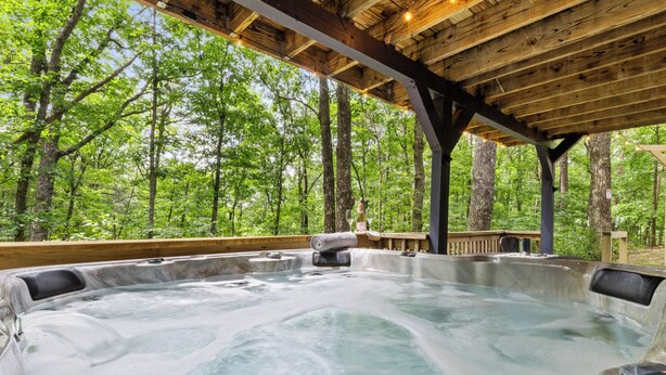 A hot tub in a forested area with a wooden deck and a covered seating area. - Winter Retreat, Hot Tub, Fire Pit, 7min to Ellijay. 16min to Blue Ridge (Ellijay)