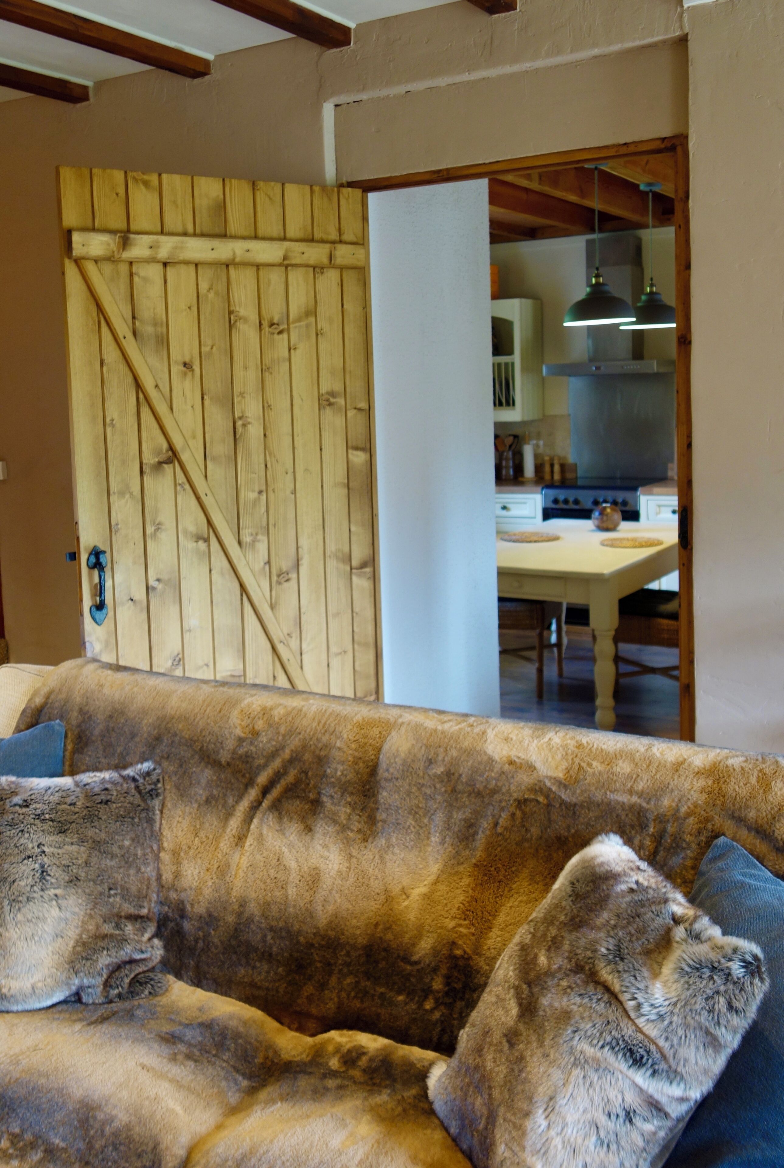 Uma sala de estar acolhedora com uma porta de madeira, um sofá e vista para a cozinha.