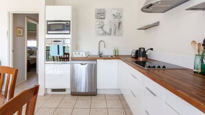 Une cuisine moderne avec des armoires blanches, des appareils en acier inoxydable et un plan de travail en bois.