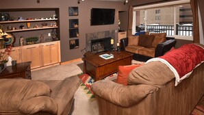 A cozy living room with a fireplace, a sofa set, a coffee table, and a bookshelf. - Lionshead Village 2 Bedroom With Pool, Walk to Slopes! (Vail)