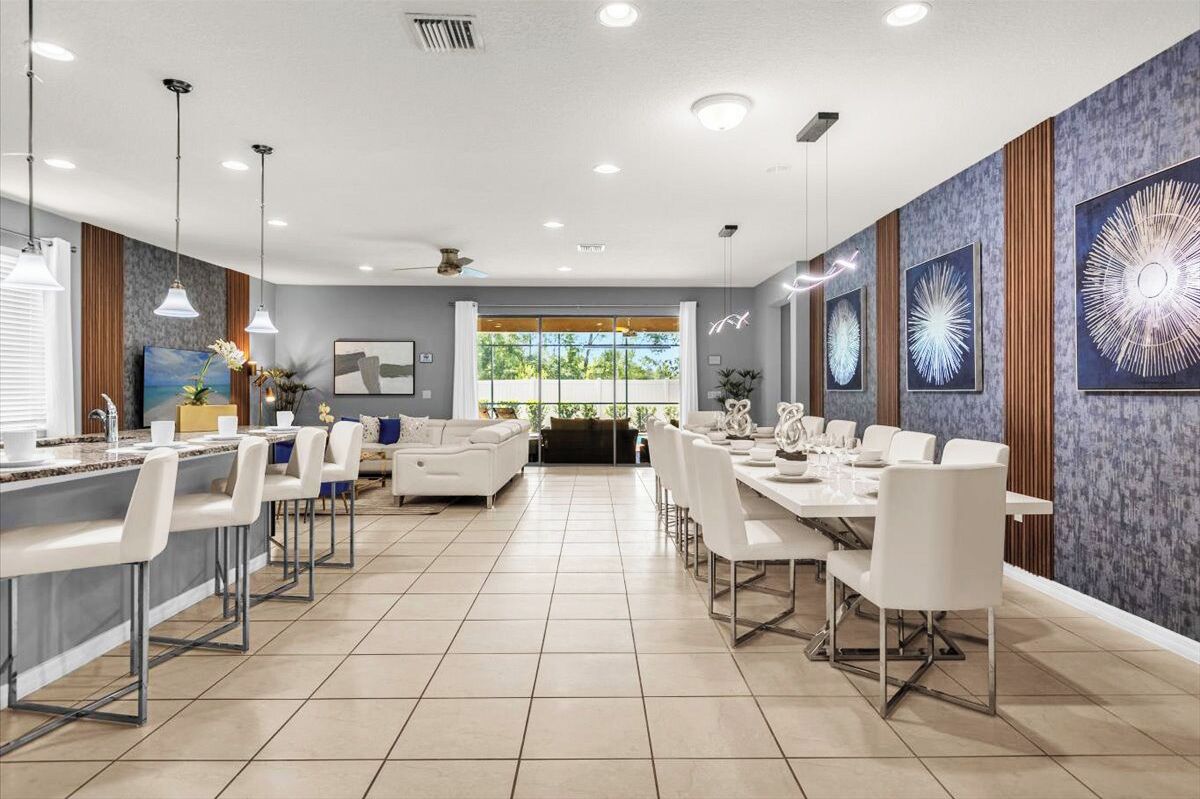 Un hall d’hôtel moderne avec un long comptoir d’accueil, un espace salon avec un canapé et des fauteuils, et un coin repas avec une longue table et des chaises.