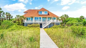 A large house with a prominent balcony and a covered walkway leading to the entrance. - The Great Escape: Oceanfront 6BR Home (Georgetown)