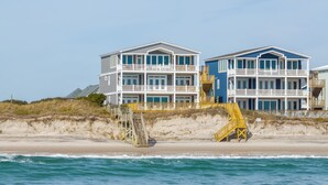 A beachfront property with multiple-story buildings, wooden staircases leading to the beach, and a clear view of the ocean. - Paradise #169 - Mini-Resort, Private Pool & Hot Tub, Sleeps 38 (North Topsail Beach)