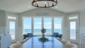 A dining room with a view of the ocean, a chandelier, and a sign that reads "Welcome to our Happy Place." - Paradise #169 - Mini-Resort, Private Pool & Hot Tub, Sleeps 38 (North Topsail Beach)