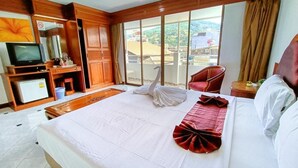 A hotel room with a large bed, a TV, a minibar, and a view of the outside. - Phuket suite hotel  (Patong)