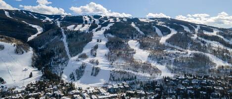 A snow-covered mountain town with ski slopes, buildings, and a clear sky.