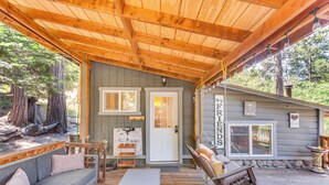 Une véranda avec un banc en bois, un coin salon avec des coussins et une petite table.