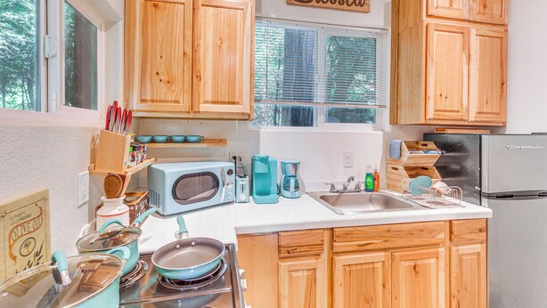 Une cuisine avec des meubles de rangement en bois, un four à micro-ondes, un grille-pain, une machine à café et un évier.
