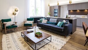 A modern living room with a sofa, chairs, a coffee table, and a kitchen area with a dining table. - Gorgeous, stylish, huge Georgian home 4 bed 4 bath (Clitheroe)