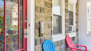 A stone building with a red door and two Adirondack chairs outside. - Pet-friendly Stoughton Apartment w/ Outdoor Space (Stoughton)