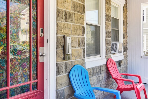A stone building with a red door and two Adirondack chairs outside. - Pet-friendly Stoughton Apartment w/ Outdoor Space (Stoughton)
