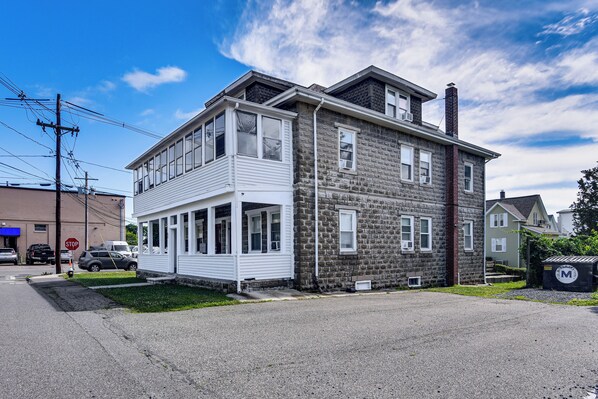 A two-story building with a balcony on the ground floor and a stone facade. - Pet-friendly Stoughton Apartment w/ Outdoor Space (Stoughton)