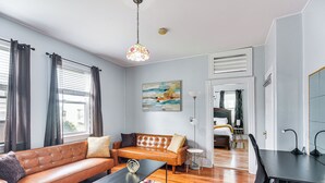 A modern living room with a leather sofa, a coffee table, and a desk with a chair. - Pet-friendly Stoughton Apartment w/ Outdoor Space (Stoughton)