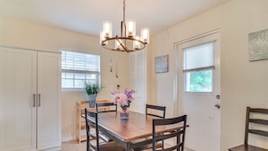 A dining area with a wooden table, four chairs, a chandelier, a potted plant, and a white door with windows. - 6 Mi to Beaches! Seminole Home w/ Furnished Patio (Seminole)