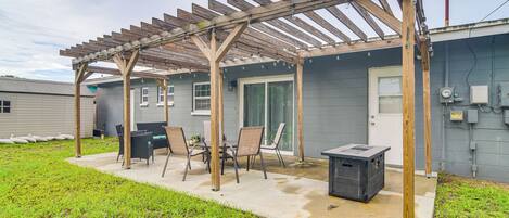 A covered patio with a wooden pergola, outdoor seating, and a grill.