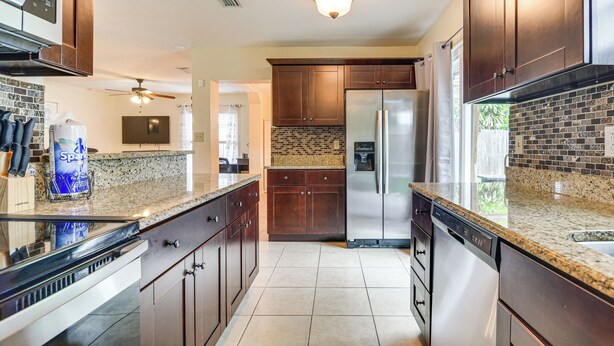 A modern kitchen with granite countertops, stainless steel appliances, and dark wooden cabinets. - 6 Mi to Beaches! Seminole Home w/ Furnished Patio (Seminole)
