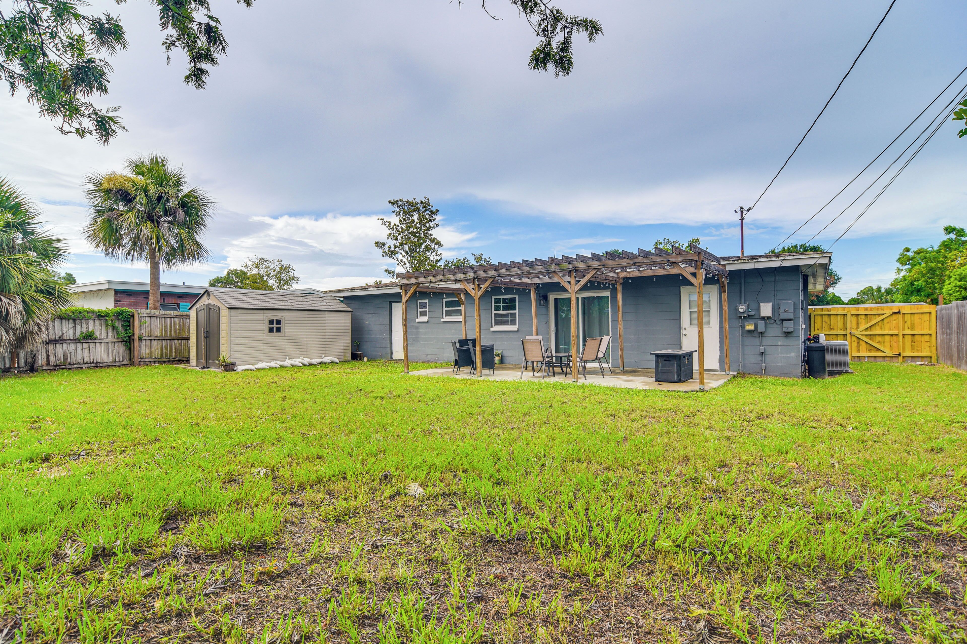 A single-story house with a covered patio, a fenced backyard, and a palm tree.