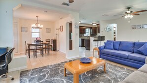 A spacious living room with a blue sofa, wooden coffee table, and a dining area with a chandelier. - 6 Mi to Beaches! Seminole Home w/ Furnished Patio (Seminole)