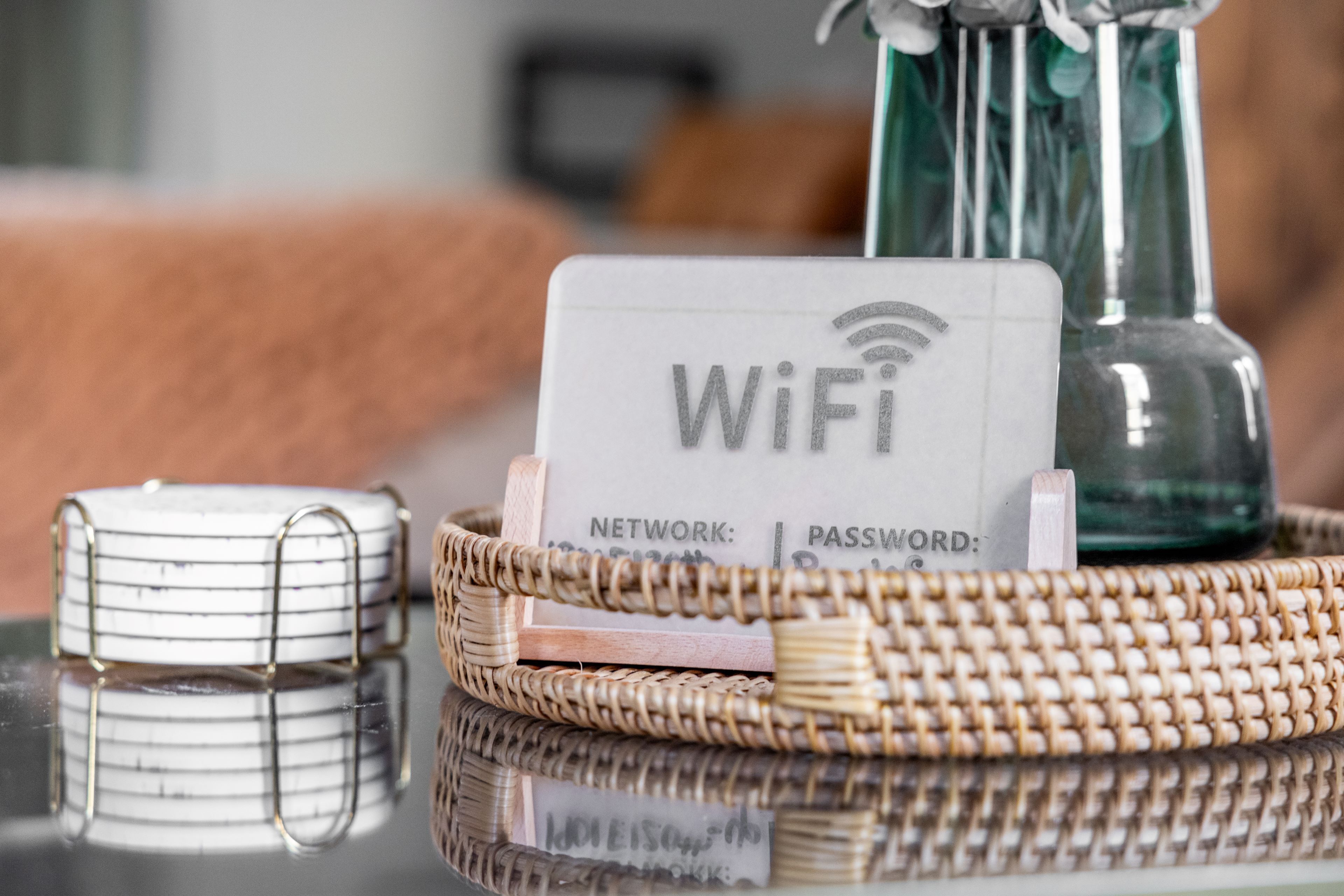 Une carte avec le mot de passe du réseau Wi-Fi, posée sur une table, à côté d’un panier en osier et d’un récipient en verre.