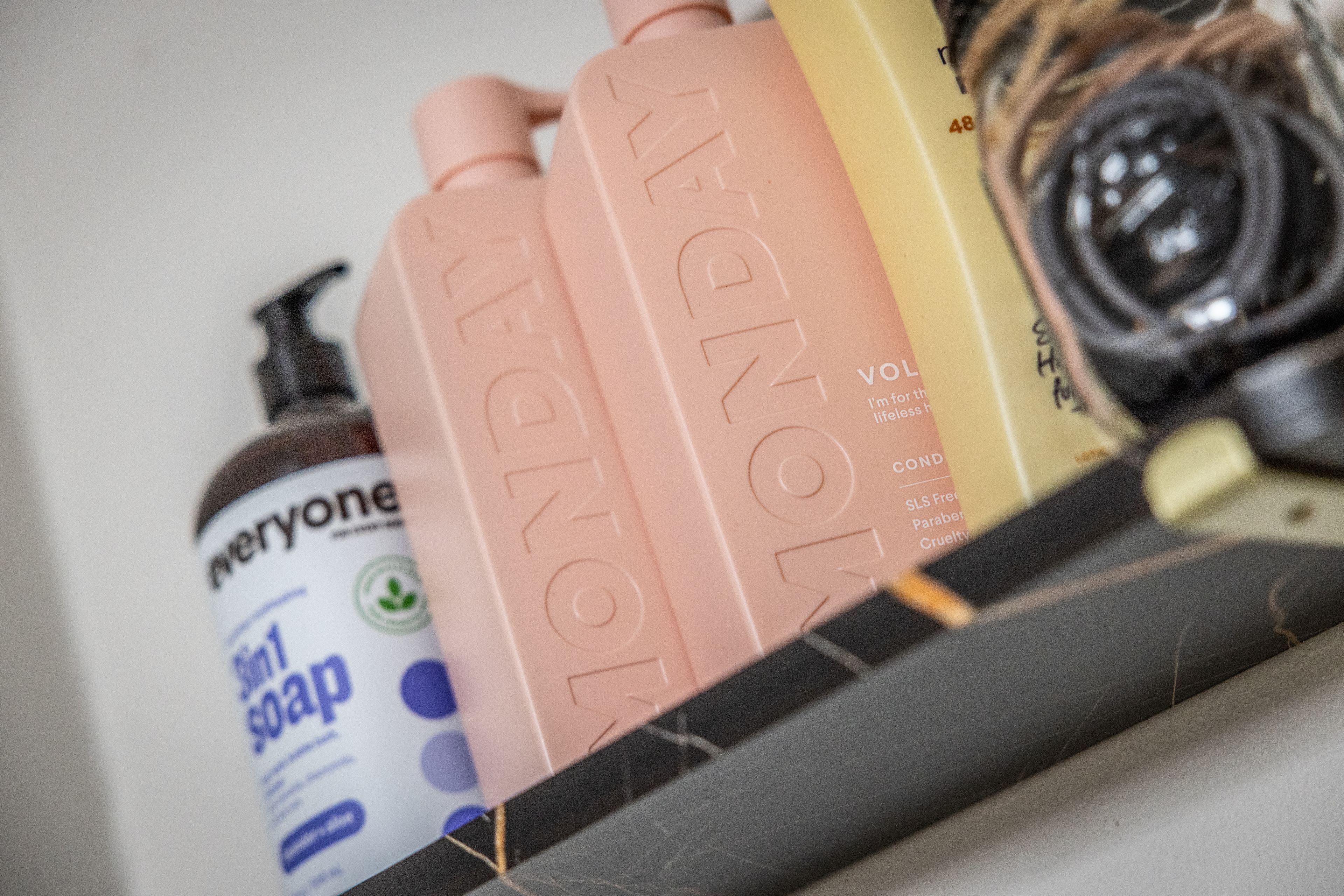A shelf with bottles of liquid soap and a camera lens.