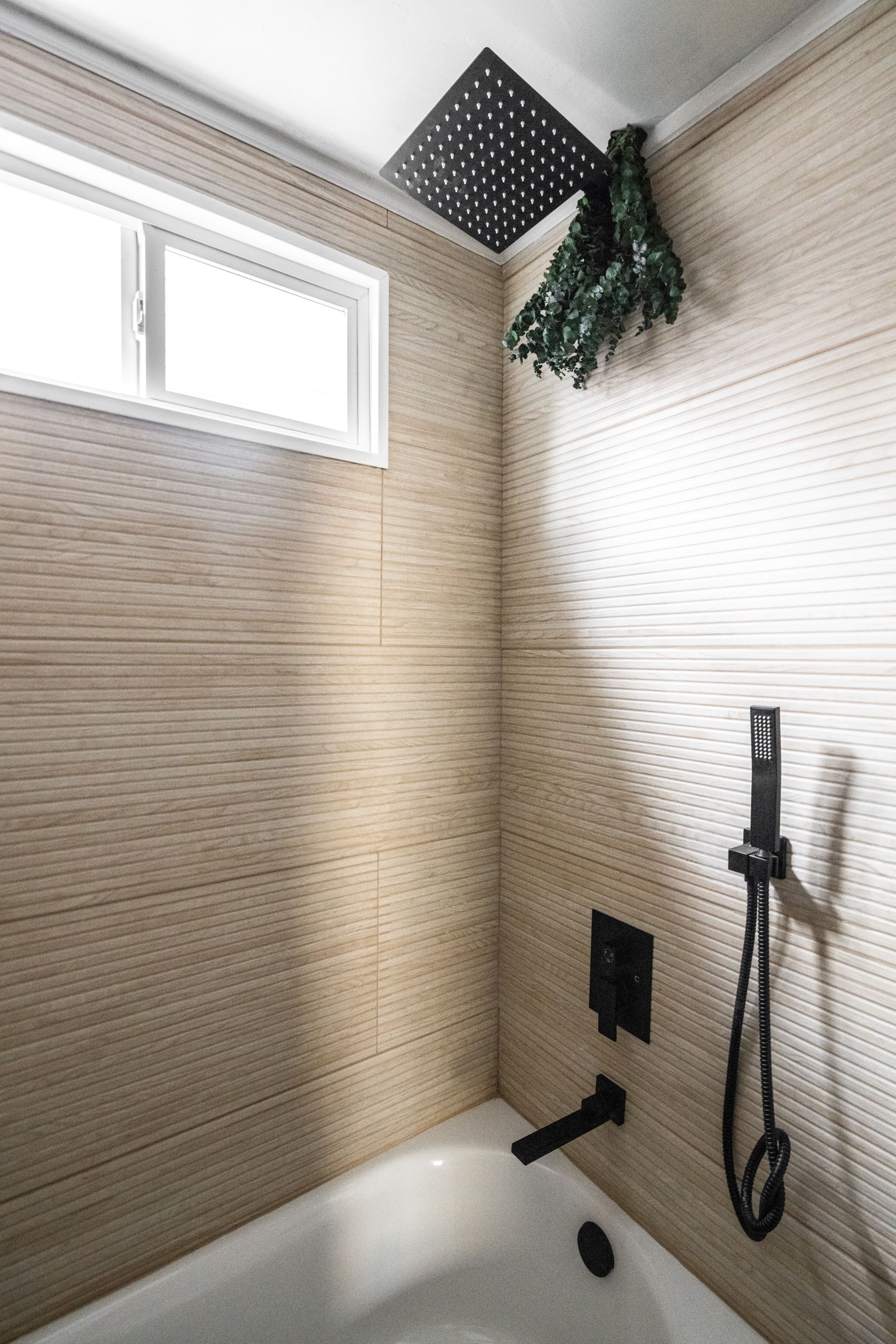 A bathroom with a shower, a window, and a wall-mounted showerhead.