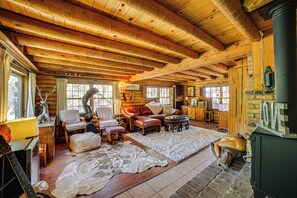 Cozy cabin with a high ceiling, leather sofa, and fireplace.