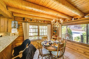 Cozy cabin with a high ceiling, exposed beams, and a large window offering a view of the outside.