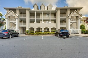 A multi-story hotel with a symmetrical facade, balconies, and a parking lot. - Calabash Condo w/ Balcony in Gated Golf Community! (Calabash)