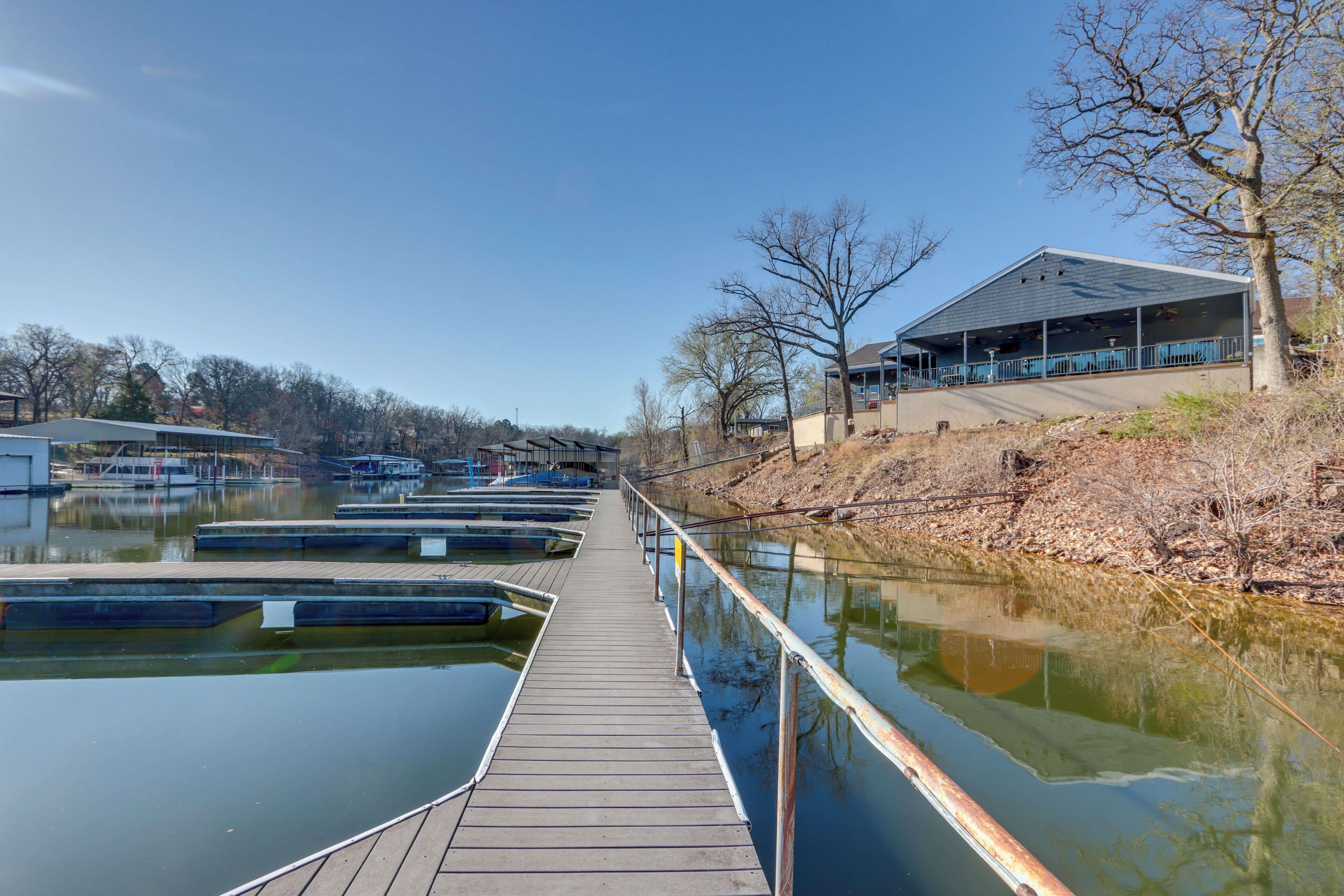 A marina with docked boats, a wooden walkway, and a building with a covered area.